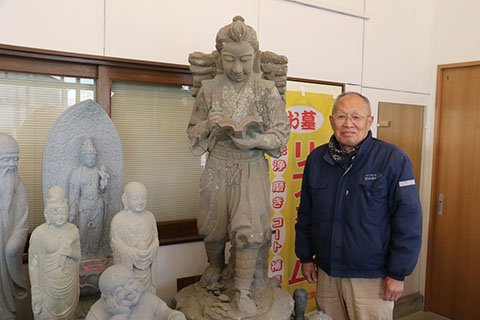 店内に展示されている初代の像と稲垣英夫さん。初代の像は岡崎の御影石製ではなく鳳来寺（新城市）近辺の石とのこと